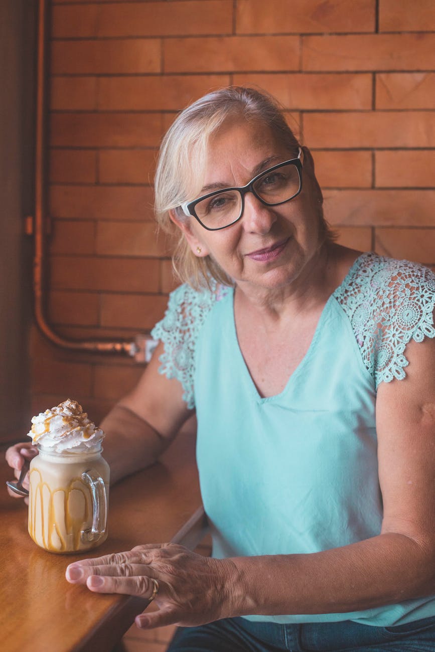 Portrait of a smiling woman with glasses in a cozy setting.